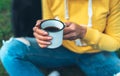 Close up girl holding in hands cup of hot tea on green grass in outdoors nature park, beautiful woman hipster enjoy drinking cup Royalty Free Stock Photo