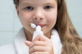 Close-up,a girl with long hair and a white coat, fooling around in the bathroom, trying to taste toothpaste Royalty Free Stock Photo