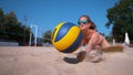 CLOSE UP: Girl playing volleyball jumps into sand and strikes ball with hand. Royalty Free Stock Photo