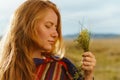 close-up girl in profile with red hair holds in her hand a bouquet of herbs and looks at it Royalty Free Stock Photo