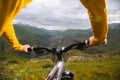 A close-up of the girl`s hand cyclist on the handlebars of a mountain bike against the backdrop of epic rocks and