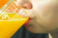Close up of girls face and lips drinking orange juice from the glass as refreshment, real people, selective focus