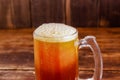 Close up of glass of beer with foam on a wooden table in a dark pub Royalty Free Stock Photo