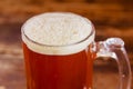 Close up of glass of beer with foam on a wooden table in a dark pub Royalty Free Stock Photo