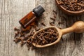 Close up glass bottle of essential clove oil and cloves in wooden shovel or spoon on wooden table