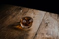 Close up of glass of bourbon whiskey with ice cubes on old wooden table isolated on black Royalty Free Stock Photo