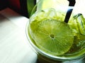 Close up glass of cold lemon green tea with iced, tube on table with sunlight shining from window. Royalty Free Stock Photo