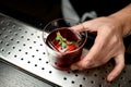 Close-up glass with cold red alcoholic drink and ice cube decorated with green plant Royalty Free Stock Photo