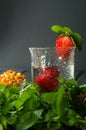 Close up. A glass of cool water with berries and mint. Grey background. Copy space