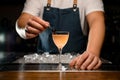 Close-up of glass of drink and hand of bartender which decorate it with berry