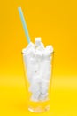 Glass full of sugar cubes over yellowbackground. Unhealthy diet and diabetes concept. Copy space for text