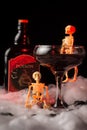 Close-up of glass of Halloween black widow cocktail with skeletons and bottle of poison on spider web