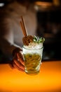 close-up of glass with iced mojito cocktail with drinking straw in male hand