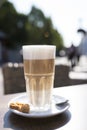 Glass of latte macchiato with spume, spoon and cookie