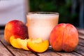 Glass of peach yoghurt and peaches on wooden table Royalty Free Stock Photo