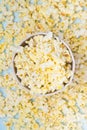 Close - up of a glass of popcorn on the background of scattered fried grains