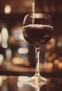 Close up of a glass of red whine with blurred background on a table with reflection