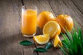 Close-up of Glass squeezed orange juice and fresh fruits ripe cut half, slice with green leaves on old wood vintage table. Royalty Free Stock Photo