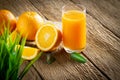 Close-up of Glass squeezed orange juice and fresh fruits ripe cut half, slice with green leaves on old wood vintage table. Royalty Free Stock Photo