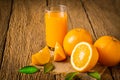 Close-up of Glass squeezed orange juice and fresh fruits ripe cut half, slice with green leaves on old wood vintage table. Royalty Free Stock Photo