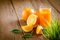 Close-up of Glass squeezed orange juice and fresh fruits ripe cut half, slice with green leaves on old wood vintage table. Royalty Free Stock Photo