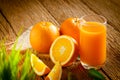 Close-up of Glass squeezed orange juice and fresh fruits ripe cut half, slice with green leaves on old wood vintage table. Royalty Free Stock Photo