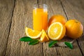 Close-up of Glass squeezed orange juice and fresh fruits ripe cut half, slice with green leaves on old wood vintage table. Royalty Free Stock Photo