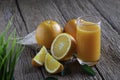 Close-up of Glass squeezed orange juice and fresh fruits ripe cut half, slice with green leaves on old wood vintage table. Royalty Free Stock Photo