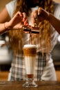 Close-up of glass with syrup and whipped cream into which barista accurate pours espresso Royalty Free Stock Photo