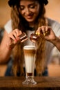 Close-up of glass with syrup and whipped cream into which barista pours espresso from cups Royalty Free Stock Photo
