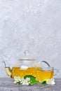 Close-up glass teapot and teacup with green tea and jasmine flowers Royalty Free Stock Photo