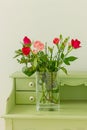 close up glass vase with bouquet of pink roses on green vintage table Royalty Free Stock Photo