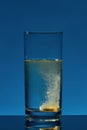 Close up of glass of water with effervescent aspirin tablet, pill in it isolated over blue background. Health concept Royalty Free Stock Photo