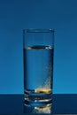 Close up of glass of water with effervescent aspirin tablet, pill in it isolated over blue background. Health concept Royalty Free Stock Photo