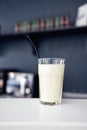 Close up of glass with white cocktail and straw. Protein shake on the counter in sports bar