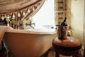 Close-up of a glass of wine and a bottle in an ice bucket on an elegant chair in the bathroom. A filled bubble bath next to the Royalty Free Stock Photo