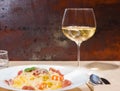 Close up of glass with wine near tasty spaghetti pasta in white Royalty Free Stock Photo