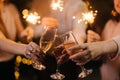 Close-up of glasses of clinking Champagne with Bengali lights. Royalty Free Stock Photo