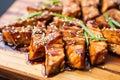 close up of glazed teriyaki tofu slices on wooden board