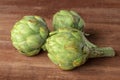 A close-up of a globe artichoke on a dark rustic wooden background