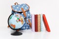 Close up of globe, blue backpack with stars print and colorful school books isolated on white background. Accessories Royalty Free Stock Photo
