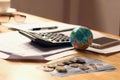 close up globe toy with calculator and money on desk office, accounting finance concept