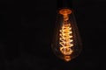 Close up glowing light bulb. Vintage lightbulb on dark background with bright yellow shining wire