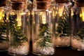 Close up of glowing lights decoration of glass jars with corks inside which there are small green Christmas trees on artificial