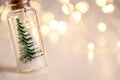 Close up of glowing lights decoration of glass jars with corks inside which there are small green Christmas trees on artificial