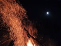 CLOSE UP: Glowing orange sparks fly out of a blazing fire into the night sky. Royalty Free Stock Photo