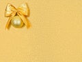 Close up gold bow with christmas ball in upper corner,rectangle shiny shimmering golden sequined backdrop,copy space Royalty Free Stock Photo