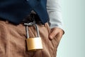 Close-up of a gold padlock hanging from a man`s belt. The concept of marital fidelity, celibacy, treason, chastity belt