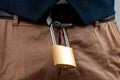 Close-up of a gold padlock hanging from a man`s belt. The concept of marital fidelity, celibacy, treason, chastity belt