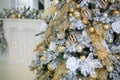 Close up golden balls and White flowers hanging on Christmas tree on background of fireplace. Shining garland. holidays and Royalty Free Stock Photo